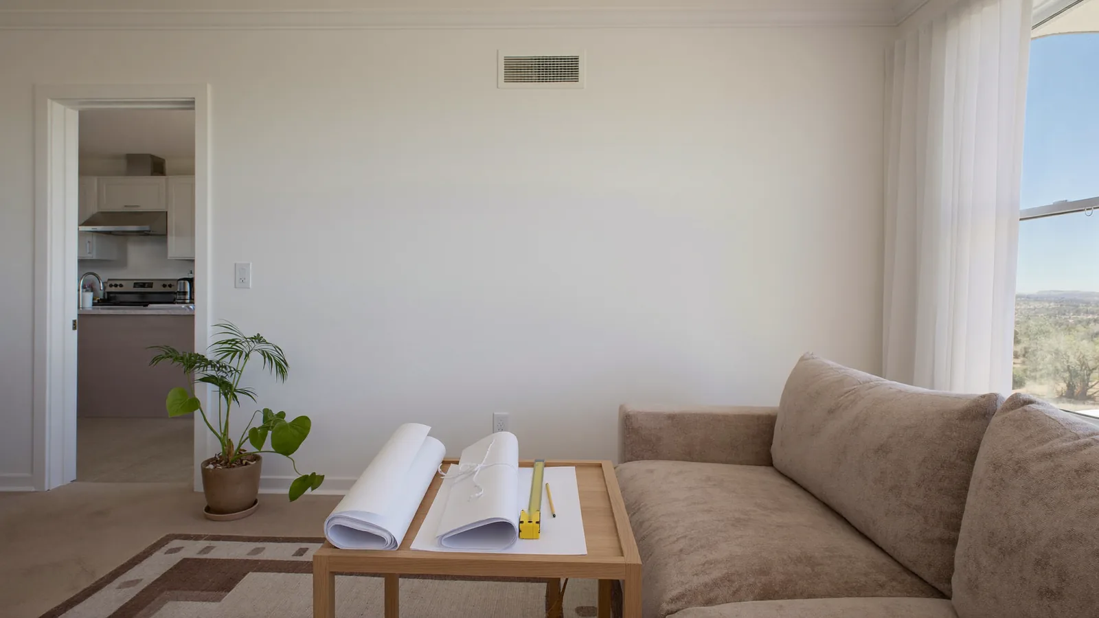 Intact interior wall and blank rolled plans on a side table, prepared for a remodeling discussion