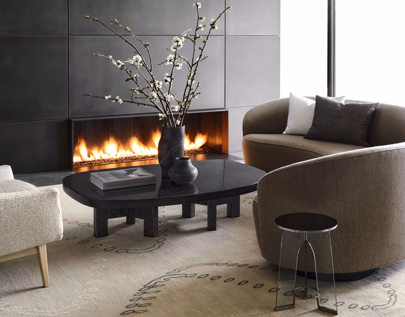 Lounge with a linear fireplace, curved armchairs and a black stone table