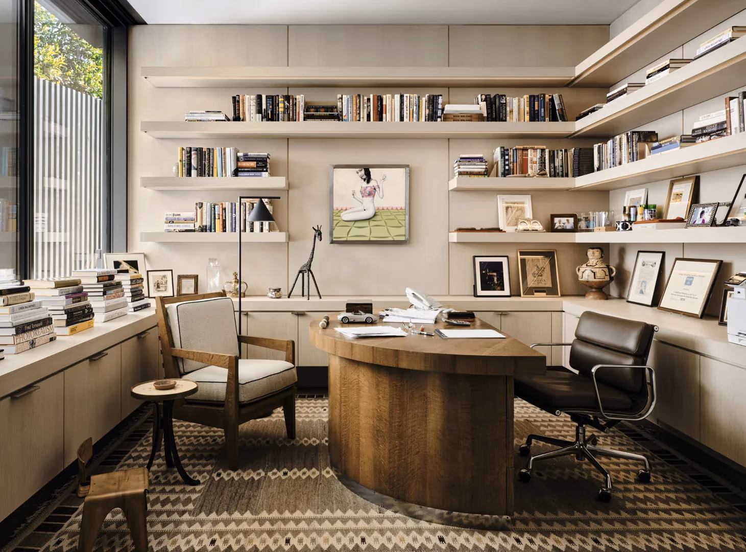 Study with wraparound shelving, a curved wood desk and a window wall